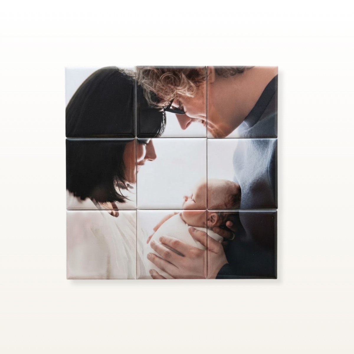 A square 3x3 mosaic tile wall art print featuring a close-up family photograph of a couple and baby, displayed on a light beige background.